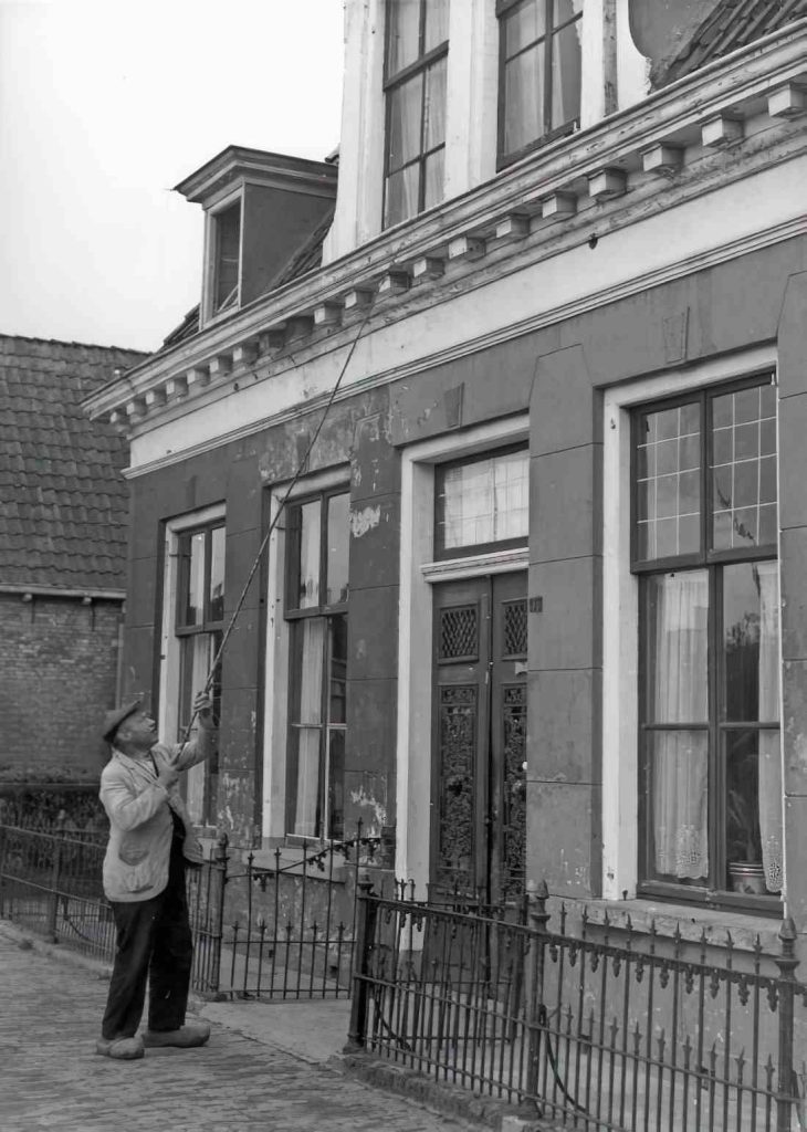 Een porder in Leeuwarden in 1947 tikt met een lange stok tegen het raam.