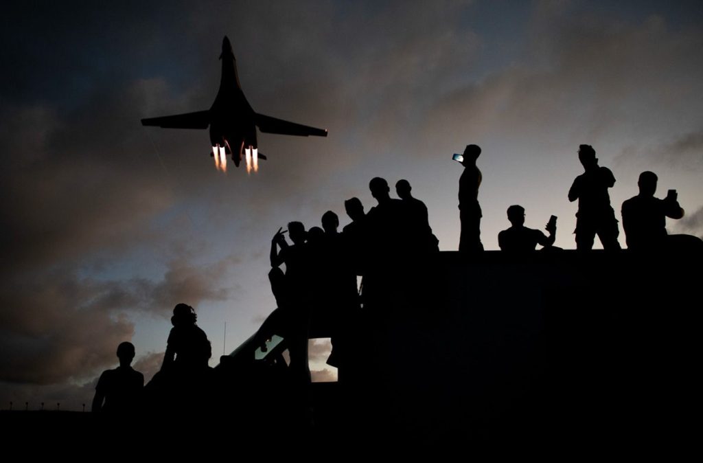 Grondpersoneel van het 9th Expeditionary Bomb Squadron kijkt toe terwijl een B-1B Lancer over Andersen Air Force Base vliegt, geschoten door River Bruce