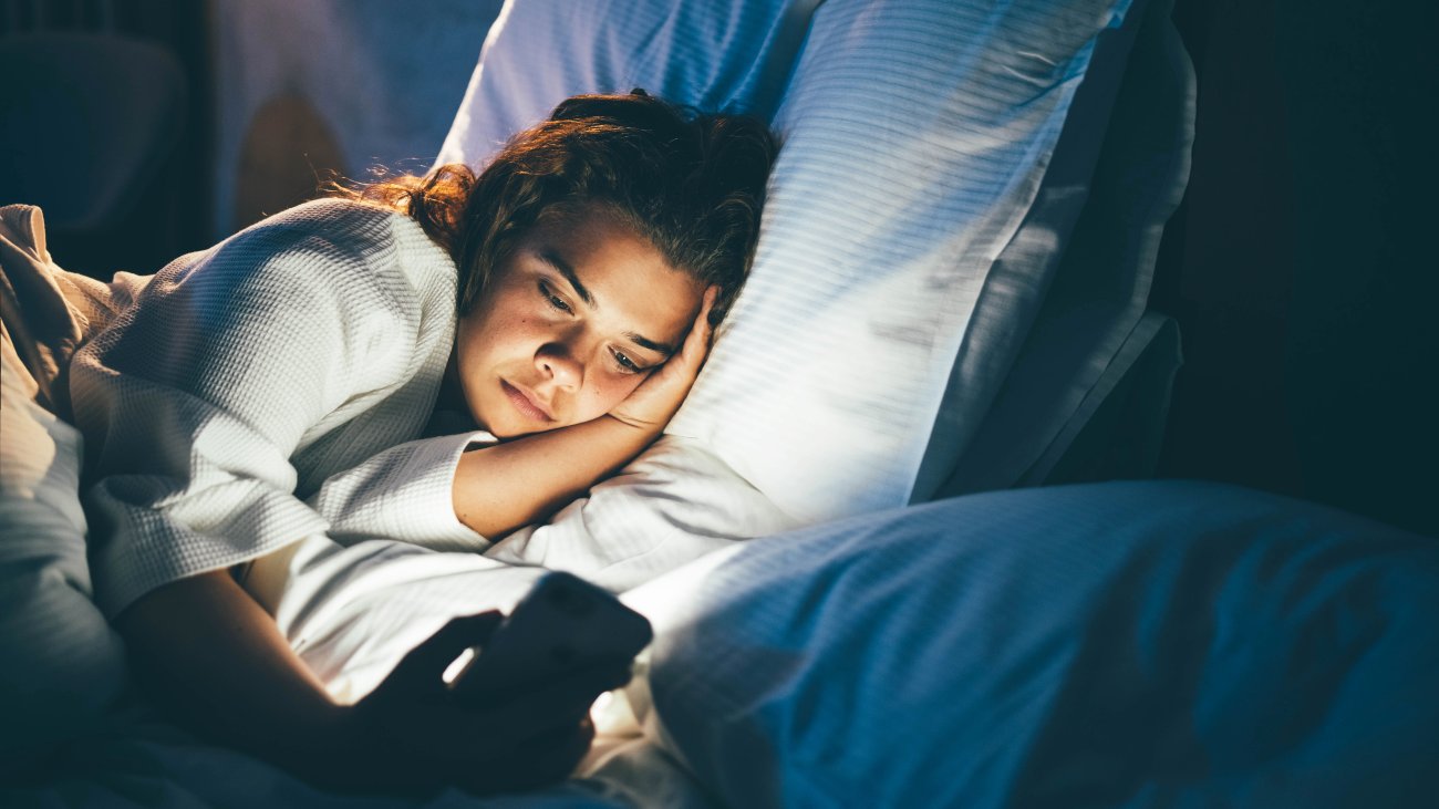 Vrouw 's nachts in bed op telefoon, superstimuli