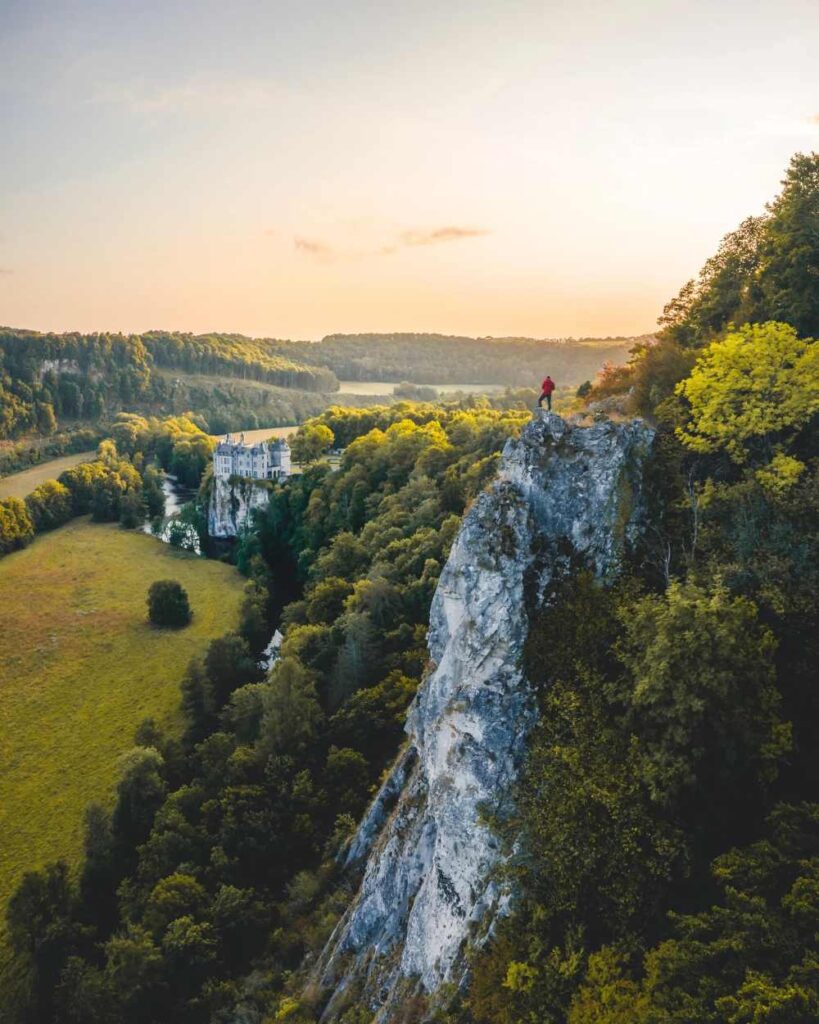 Dronefoto van man op hoge rots die kijkt naar het Kasteel van Walzin